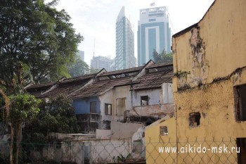 Гротескное сочетание - на переднем плане полуразвалившийся дом, на заднем плане небоскреб в стиле хайтек